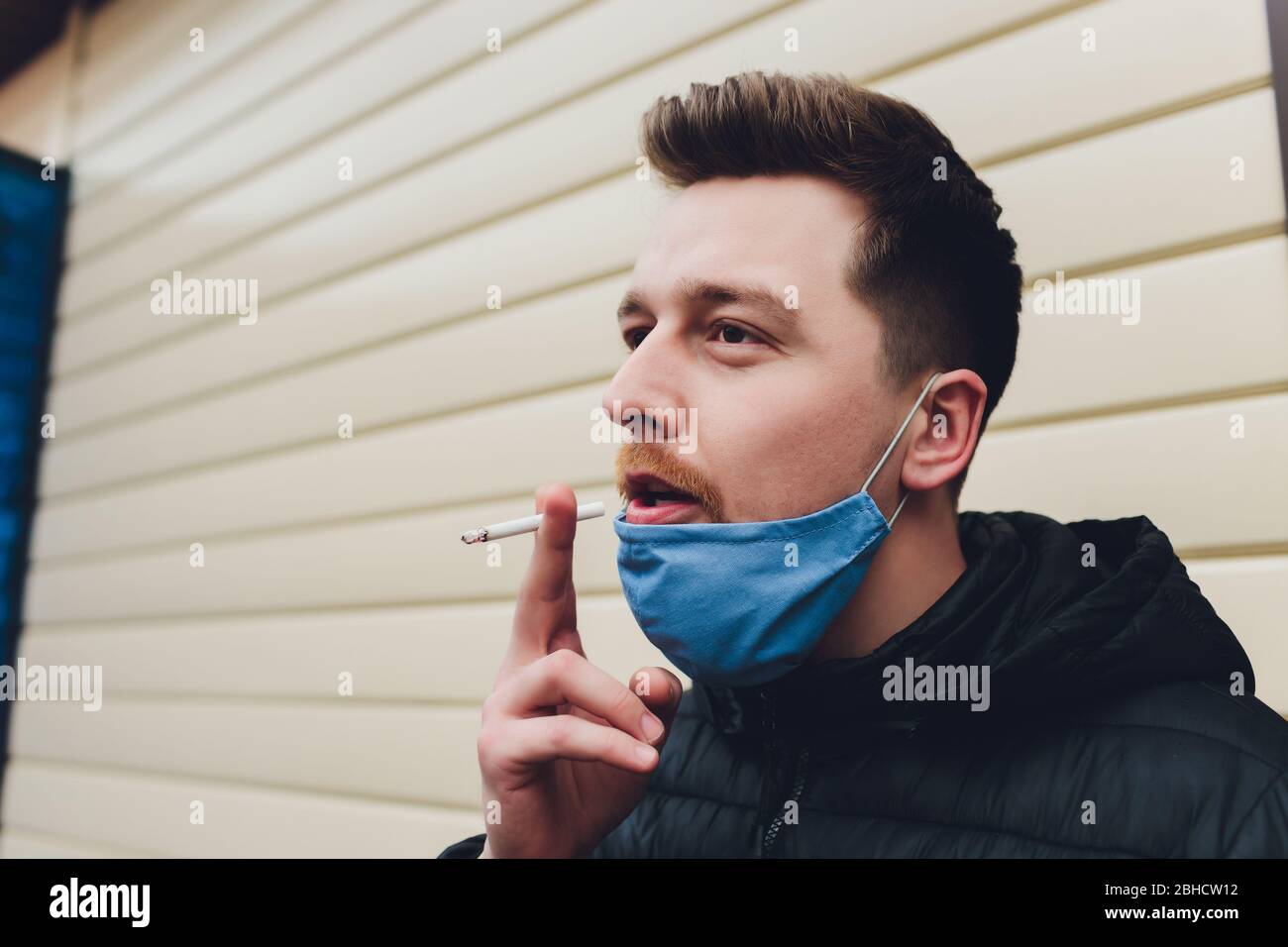 Smoking. Closeup man with mask during COVID19 pandemic smoking a