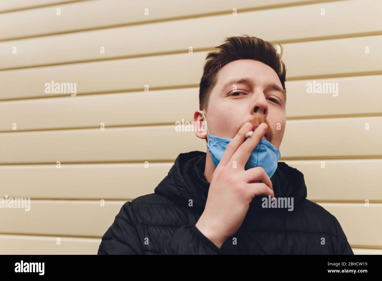 Smoking. Closeup man with mask during COVID-19 pandemic smoking a ...