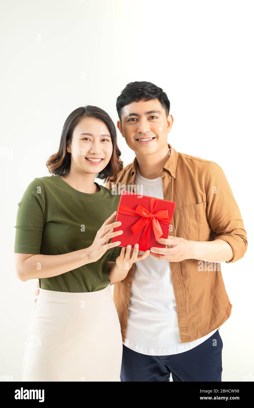 Portrait of happy couple in casual wear standing, holding box with present and looking at camera together Stock Photo