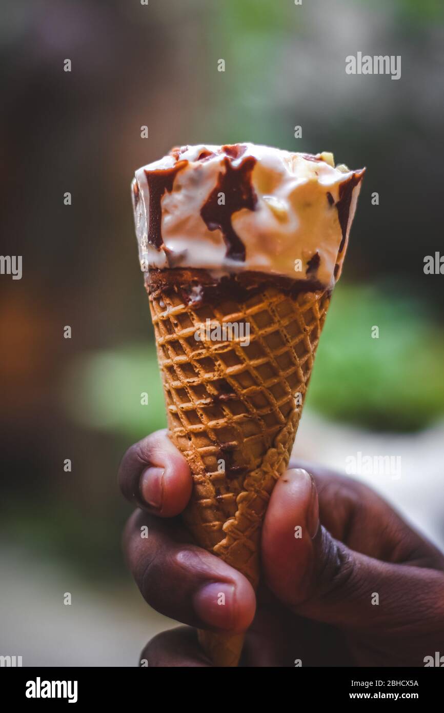 Boy hand holding an butterscotch ice cream cone with cashew nuts ice