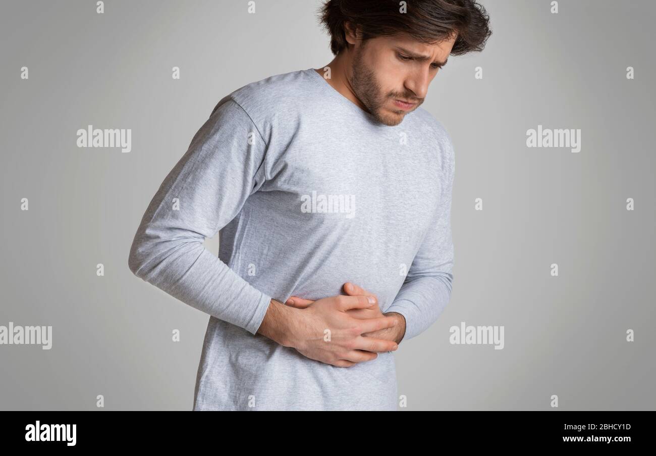 Man hands on stomach, having aches pain. Food poisoning, cramps Stock Photo