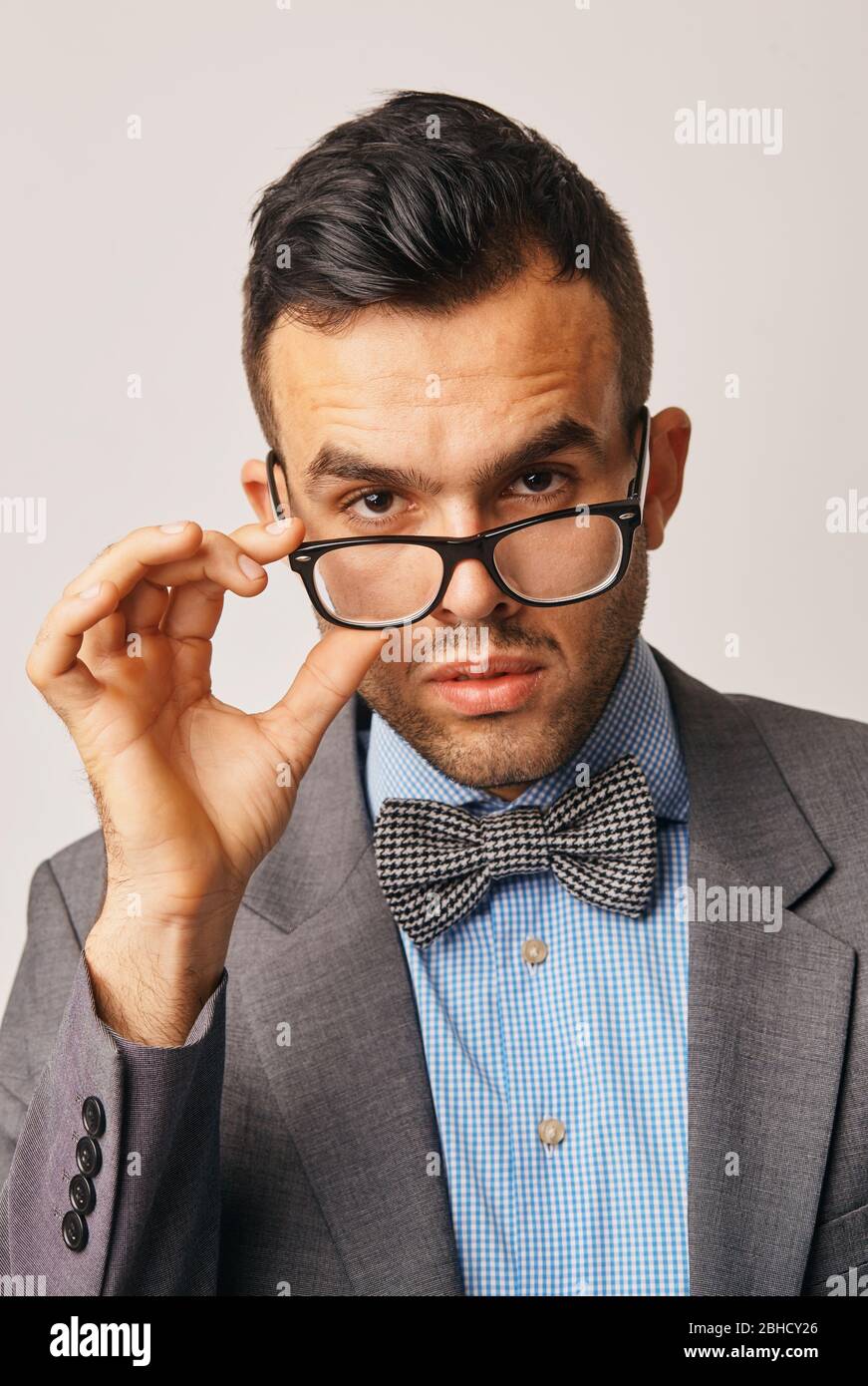 guy wearing glasses looking away and leaning on grey wall. Portrait of young businessman with eyeglasses thinking about his carrer with copy space Stock Photo