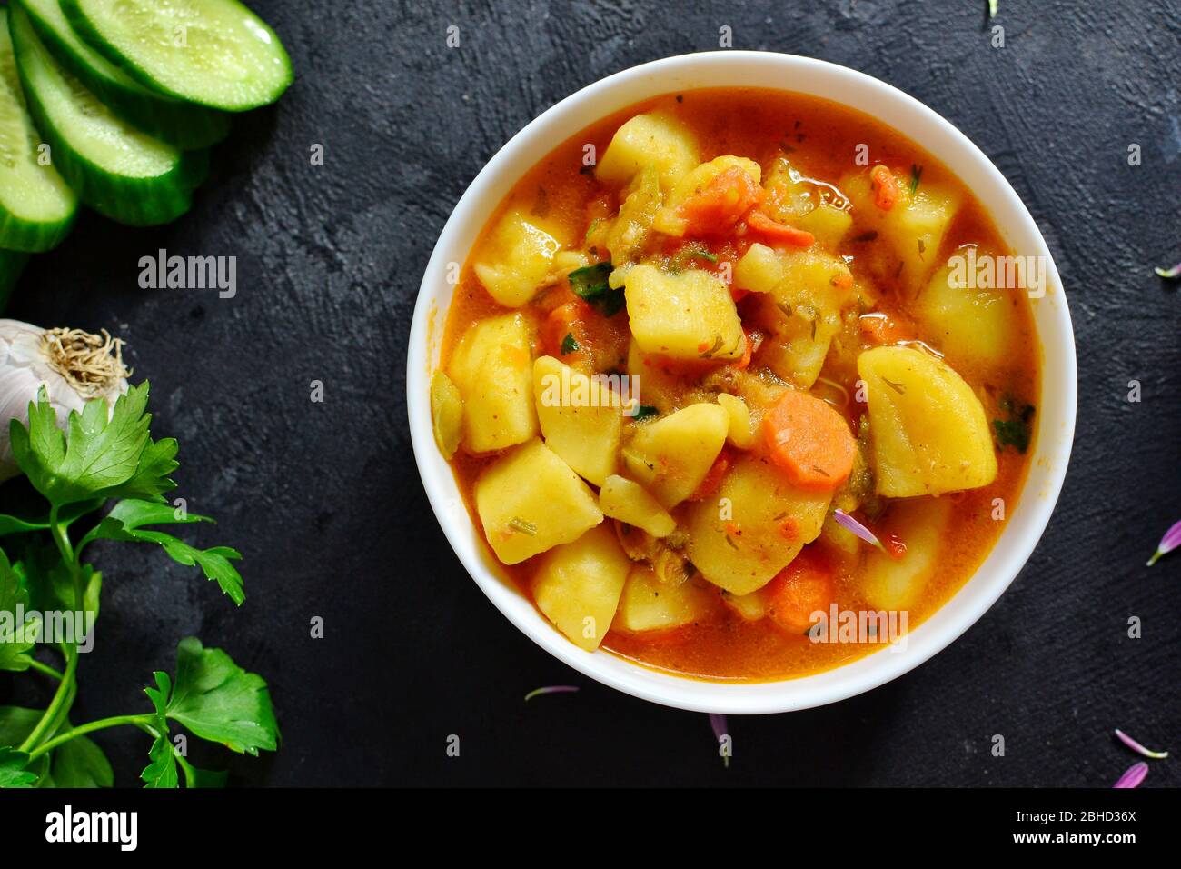 Vegetable stew in a white bowl. Photo food. Stew with potatoes and carrots on a dark concrete background. Healthy vegetarian food. Top view Stock Photo