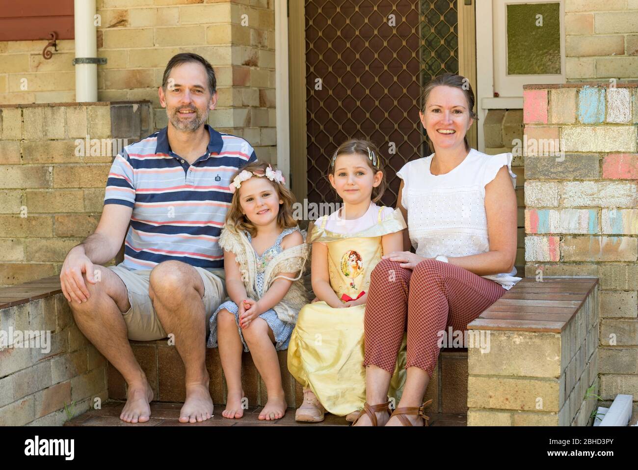 A smiling Zimbabwean family living in Australia sit at the front steps of their Sydney home during the Covid-19 epidemic. Stock Photo