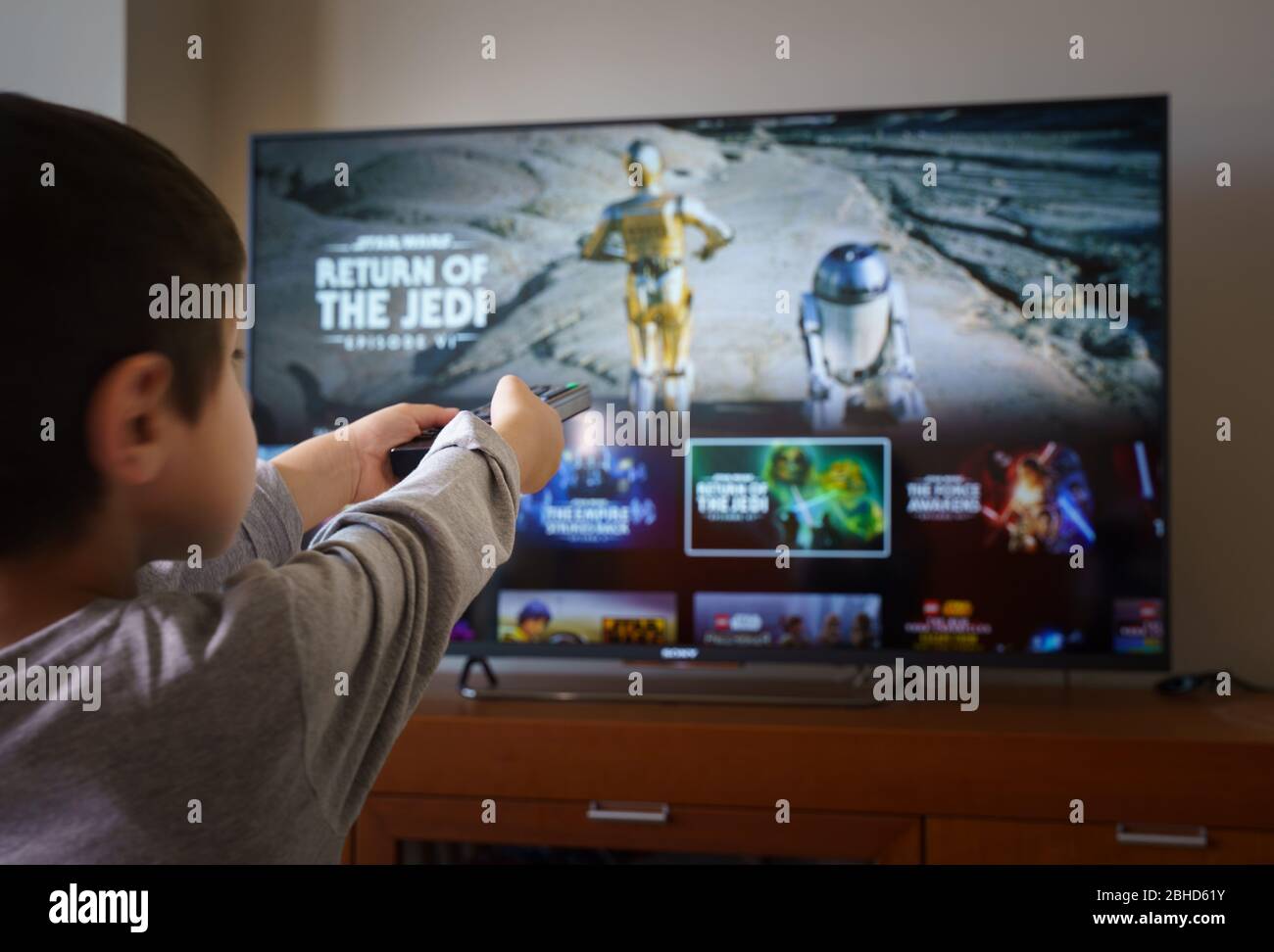 Barcelona, Spain. April 2020: Back view image of cute little boy watching Star Wars series movie and pointing at the TV screen. Stock Photo