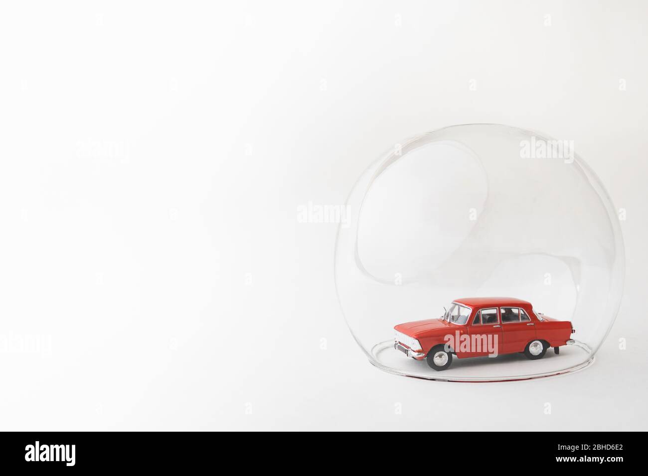 Red toy car inside a glass ball. Conceptual image of insurance coverage and safety protection. Stock Photo