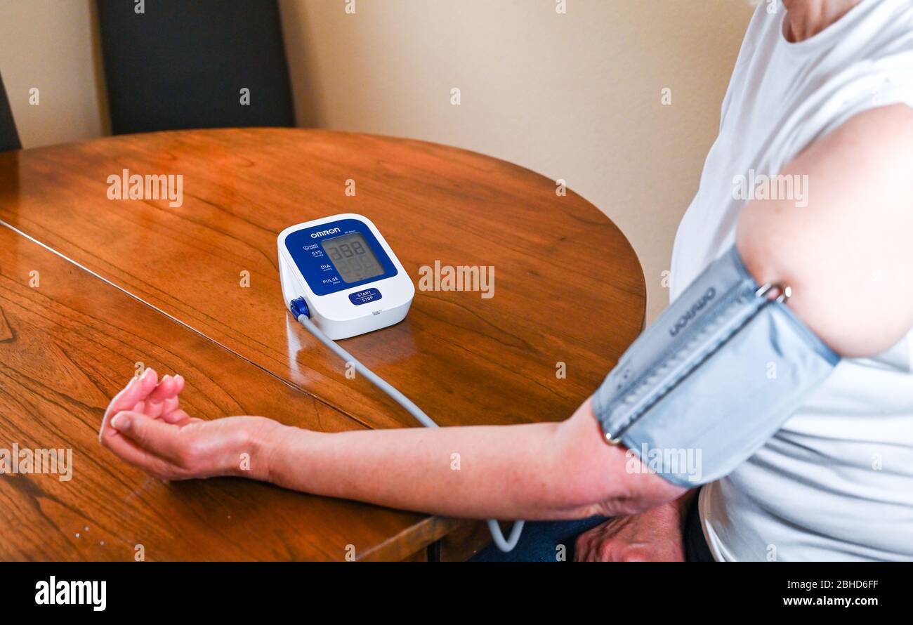 Middle aged woman using an Omron Blood Pressure testing monitor at home  Photograph taken by Simon Dack Stock Photo
