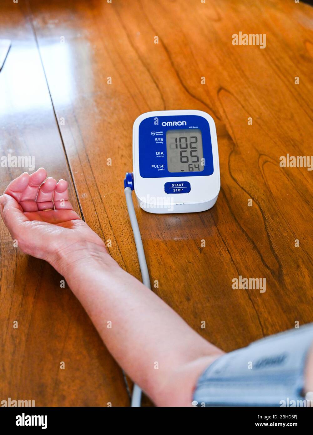 Middle aged woman using an Omron Blood Pressure testing monitor at home  Photograph taken by Simon Dack Stock Photo