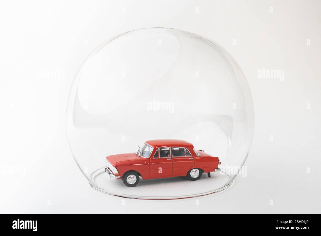 Red toy car inside a glass ball. Conceptual image of insurance coverage and safety protection. Stock Photo