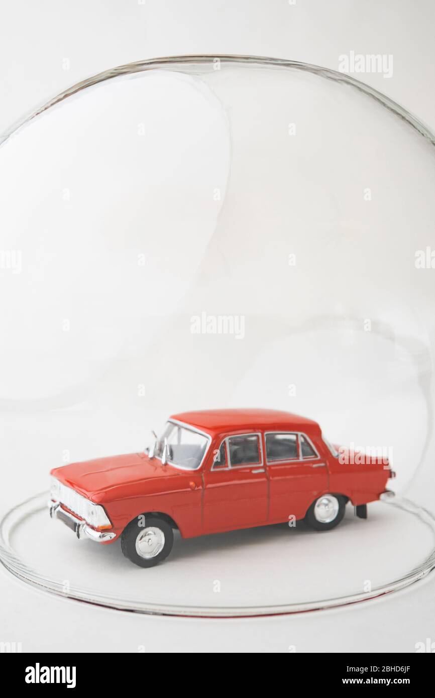 Red toy car inside a glass ball. Conceptual image of insurance coverage and safety protection. Vertical orientation. Stock Photo