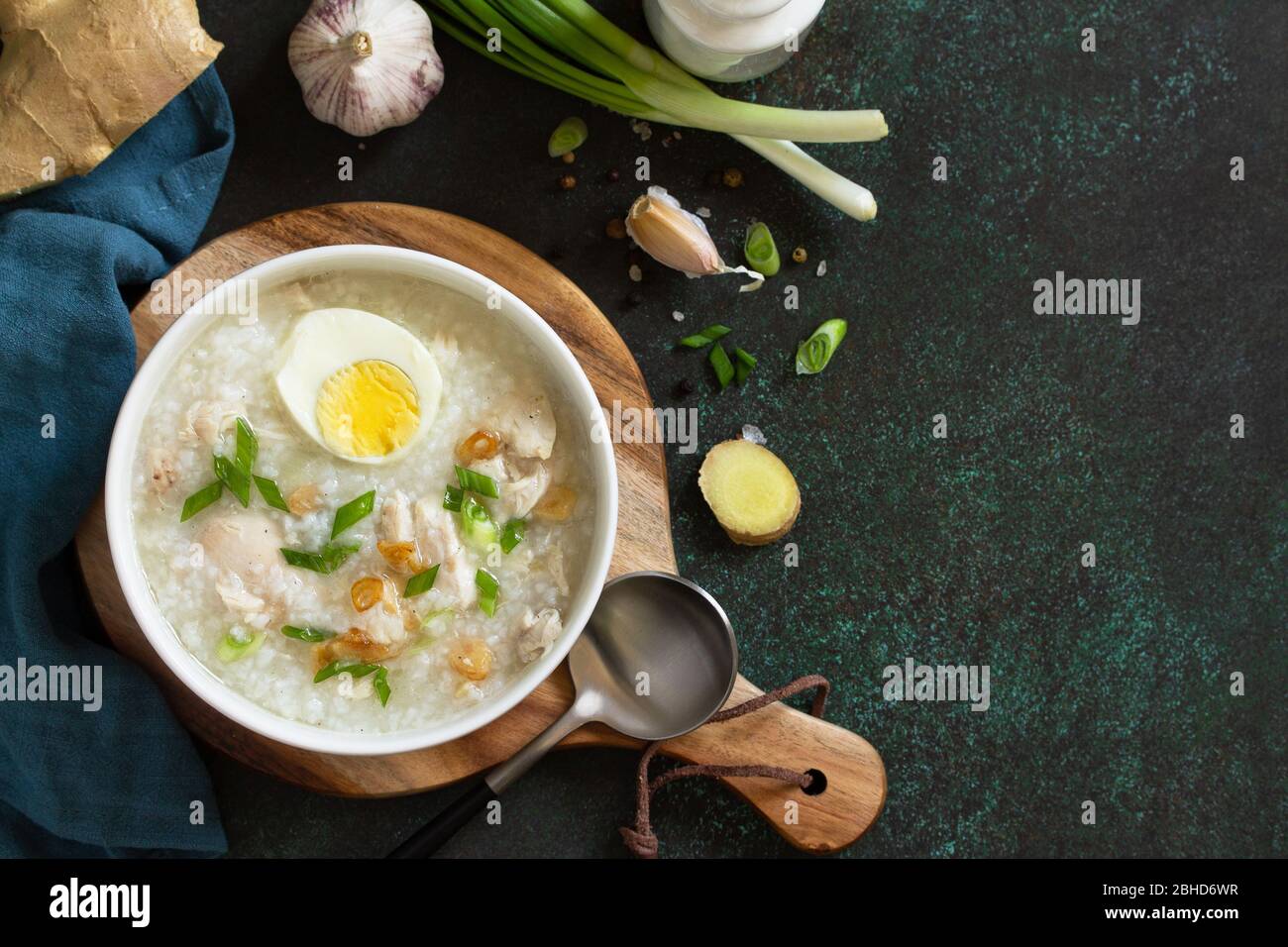 Arroz Caldo Soup. Hot soup with ginger chicken rice and garlic in a bowl on a dark countertop. Top view flat lay background. Copy space. Stock Photo