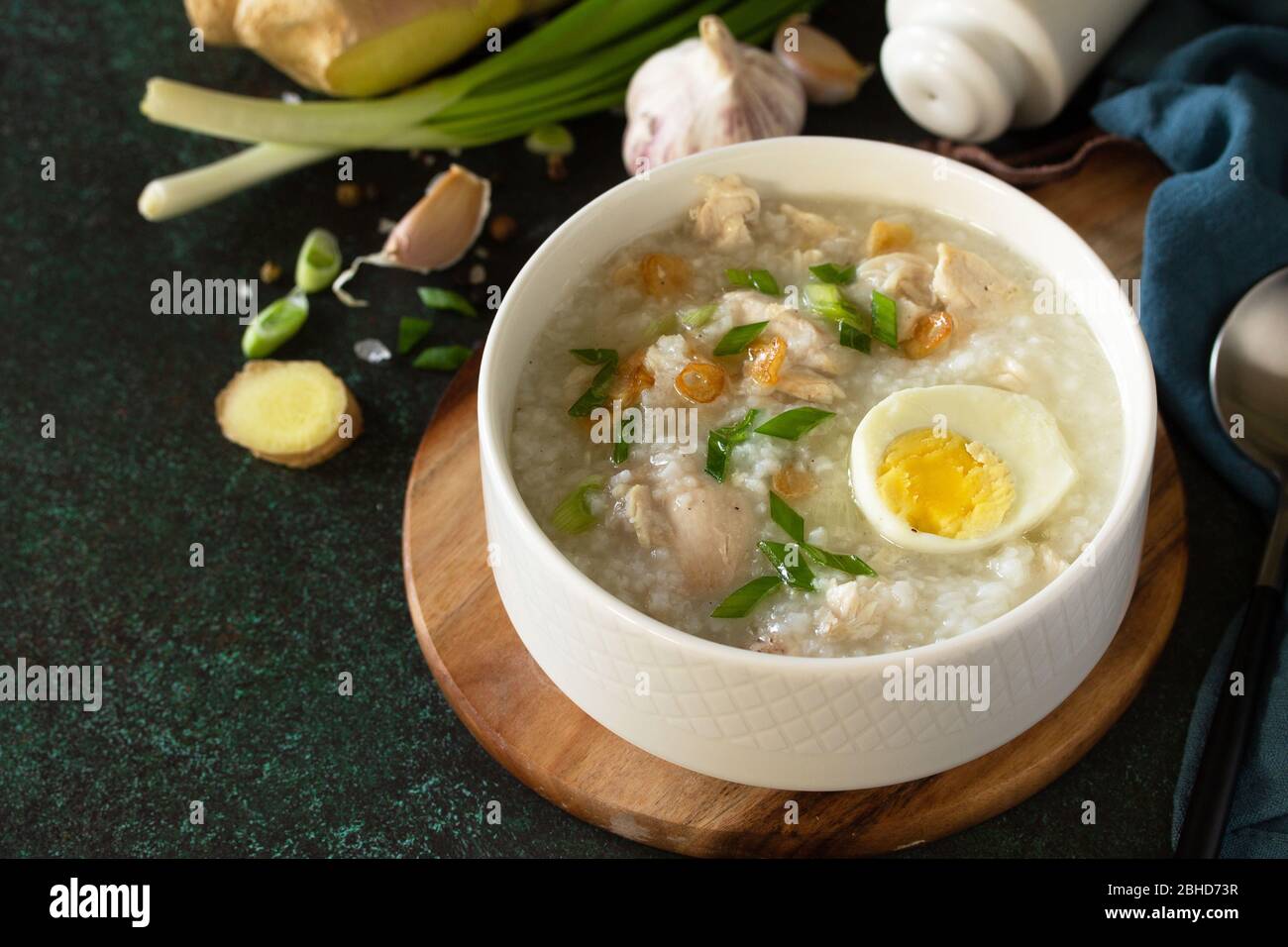Arroz Caldo Soup. Hot soup with ginger chicken rice and garlic in a bowl on a dark countertop. Copy space. Stock Photo