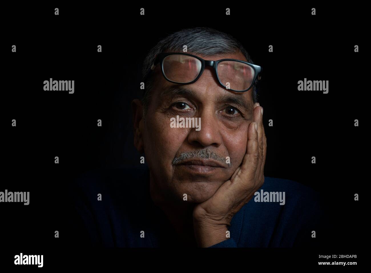 Close up portrait of thinking senior man on black background Stock Photo