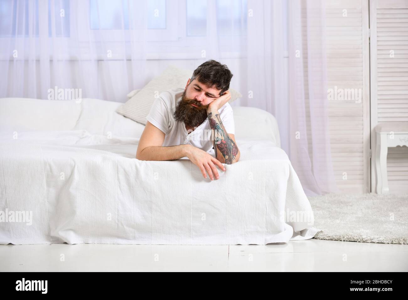 Guy on calm face sleeping on edge of bed. Exhausted concept. Macho with