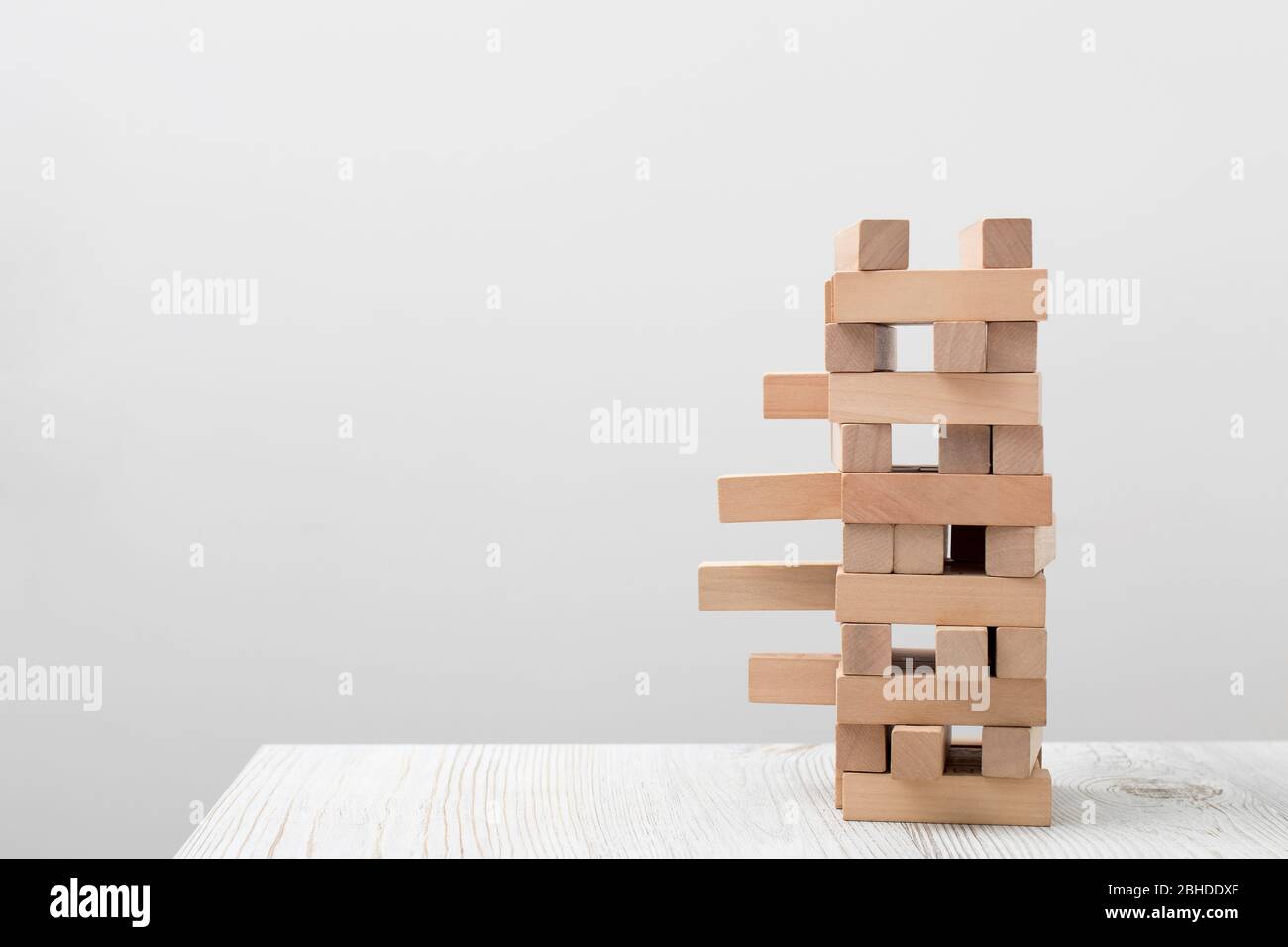 Tumbling tower is on the white tableopposite wall. Space for text. Copy space. Concept Stock Photo