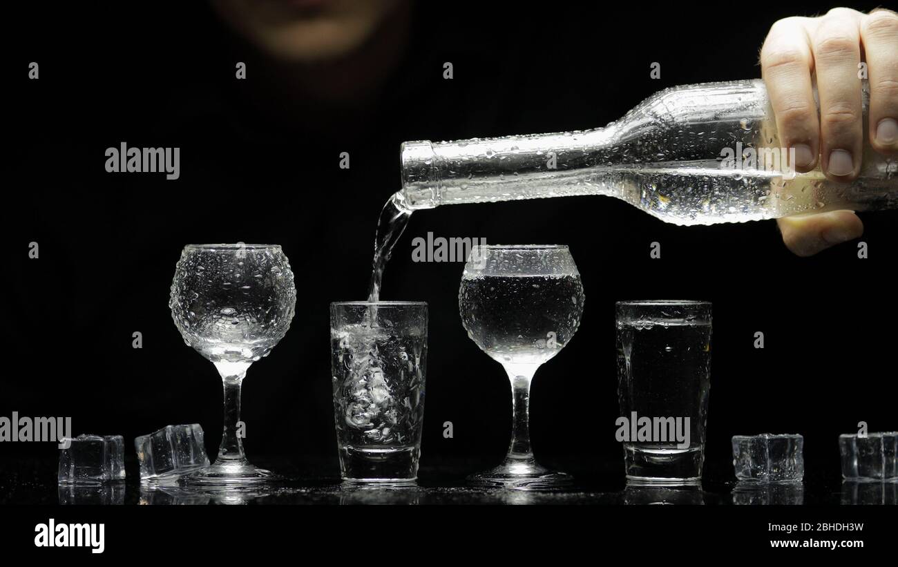 Bartender pouring up frozen vodka from a bottle into four shots glasses
