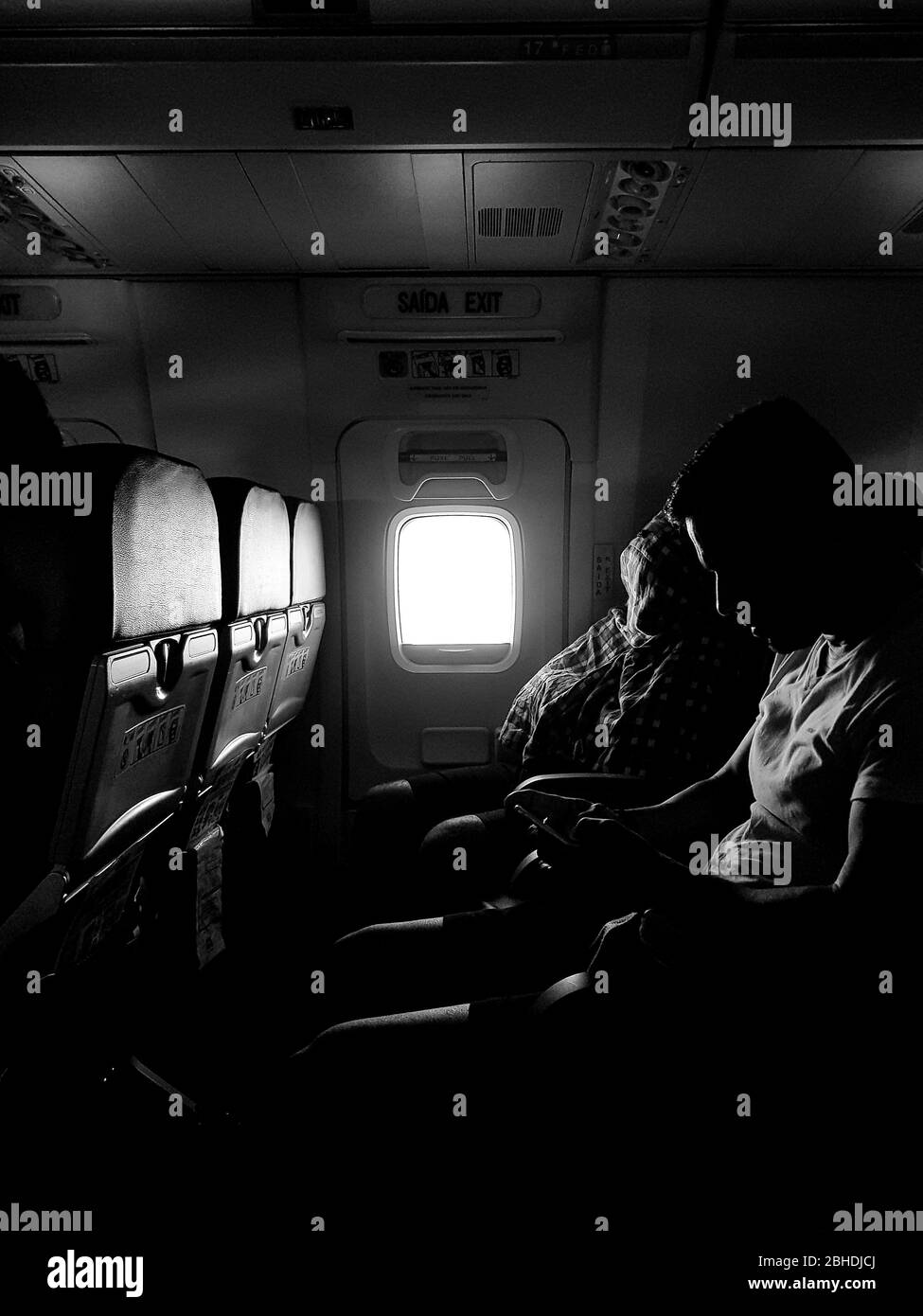 black and white photo of two people sitting in commercial plane Stock Photo