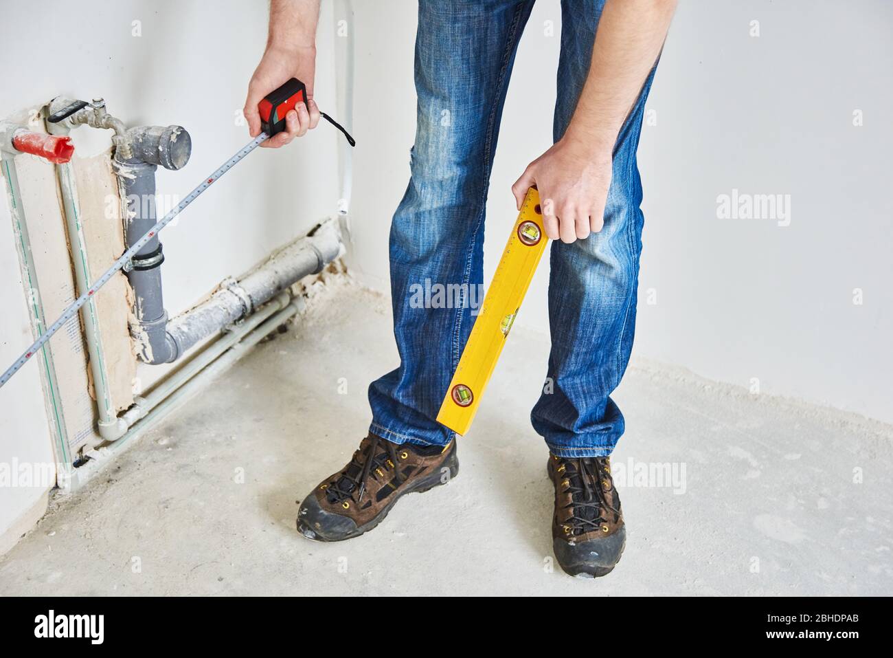 Plumber checks pipe vertical level after installation. Man with tape
