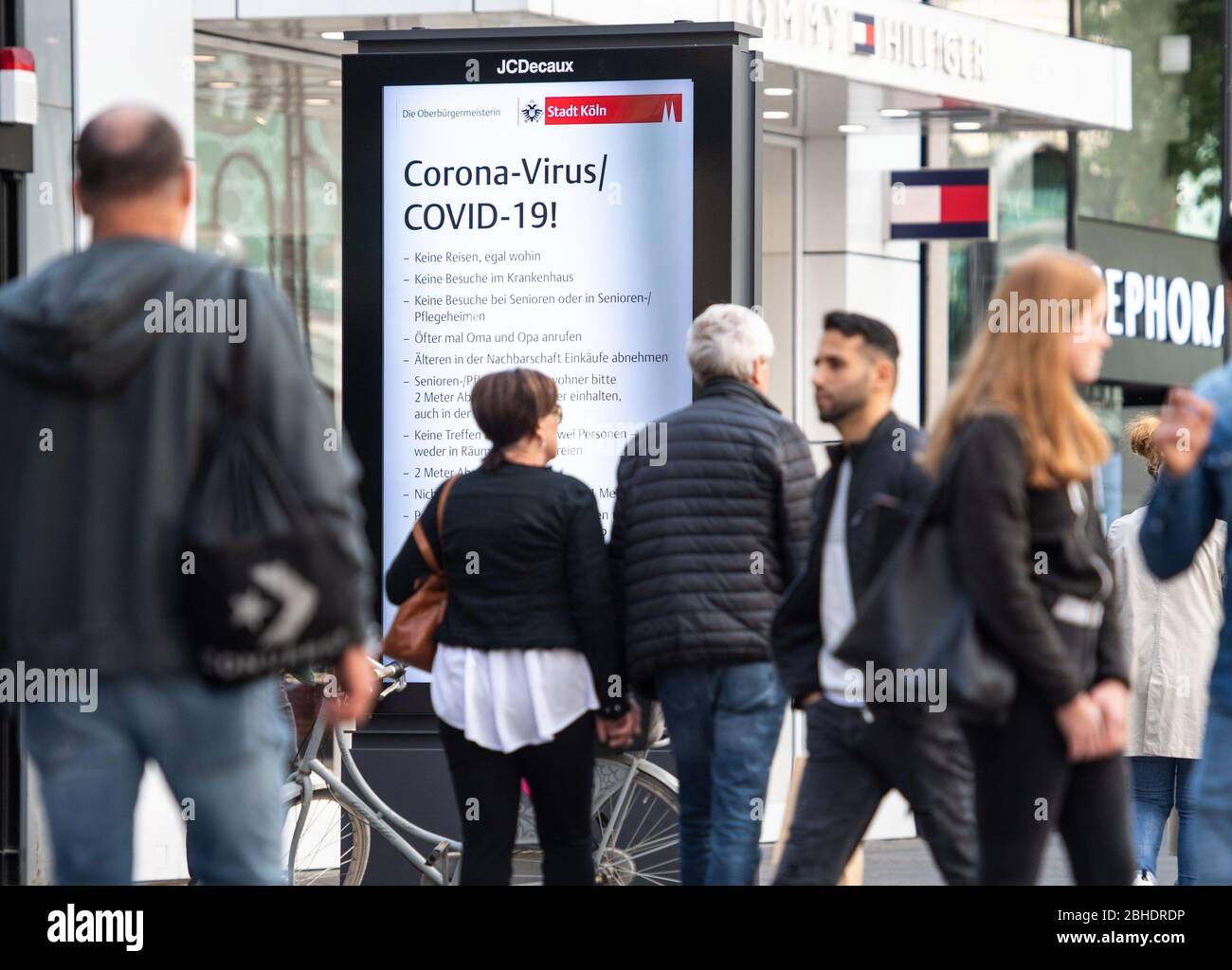 Cologne, Germany. 25th Apr, 2020. Passers-by walk along the Schildergasse past an advertising board displaying behavioural instructions for the corona pandemic. Credit: Marius Becker/dpa/Alamy Live News Stock Photo