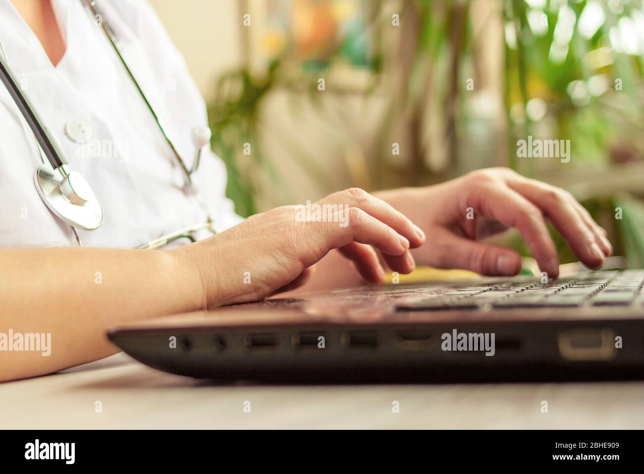 Female medical doctor wearring white uniform and stethoscope working online from home office Stock Photo
