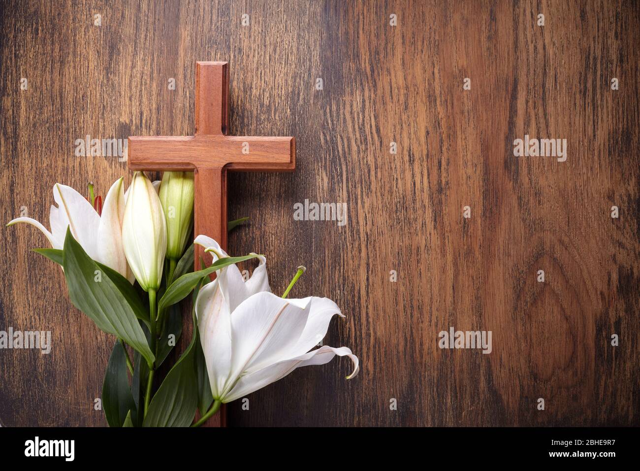 Wooden cross and white lily on rustic table Stock Photo