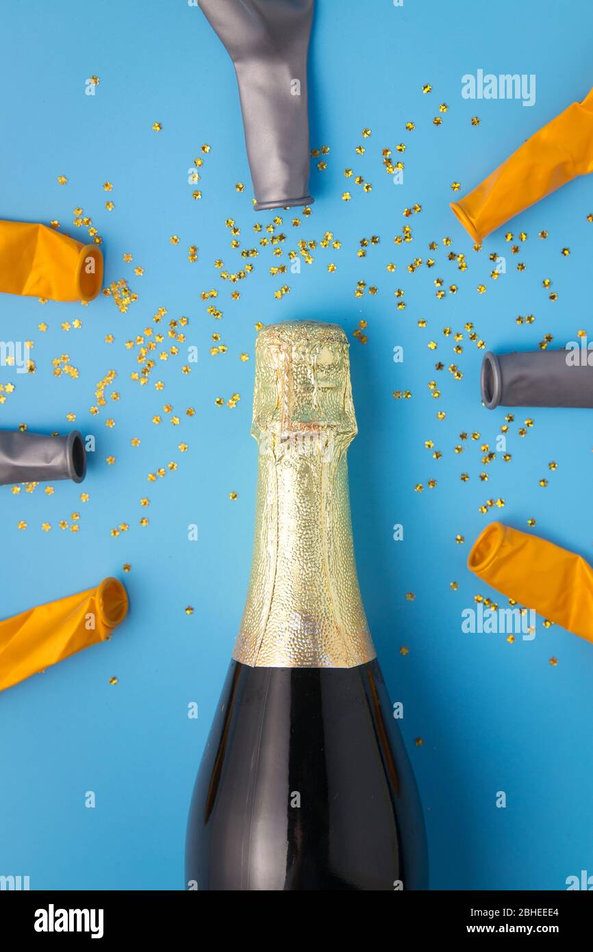 Flat lay of celebration, Champagne bottle and balloon on blue background with glitter. Stock Photo