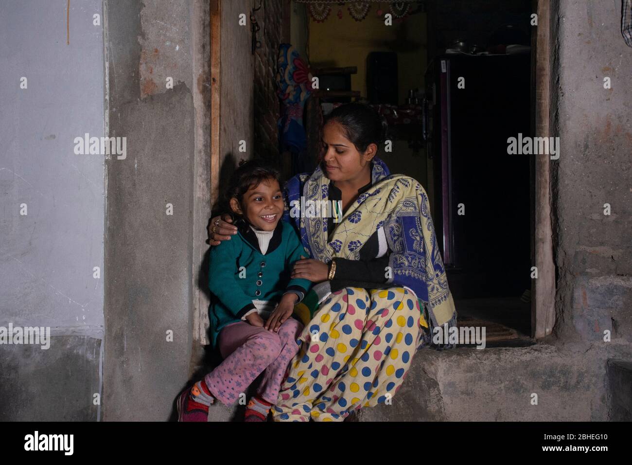 indian rural mother and daughter sitting at door of the house Stock Photo