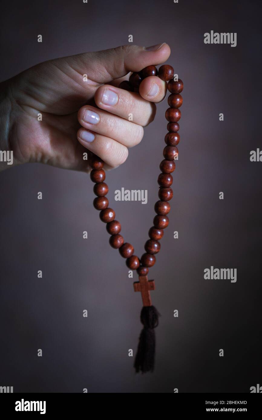 womans hand with wooden rosary or prayer beads Stock Photo