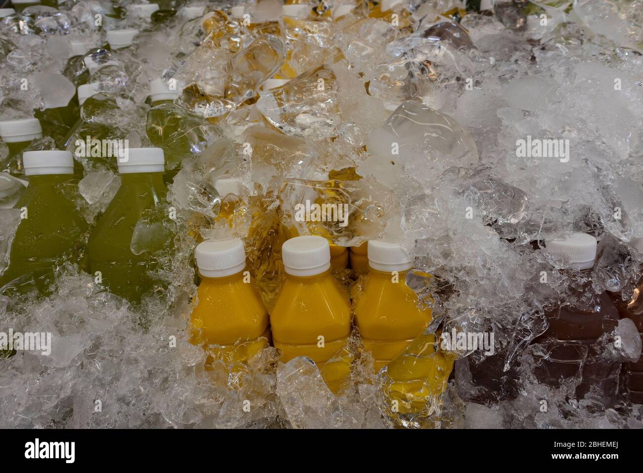A bottled variety fruit drinks covered with ice to keep them chilled