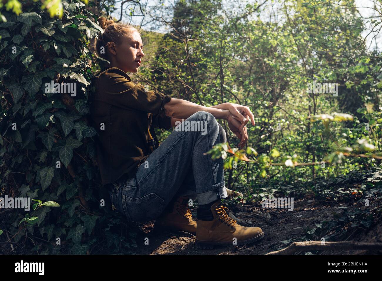 Girl with closed eyes resting, leaning against tree. Tourism Hiking Survival Bushcraft Concept Stock Photo