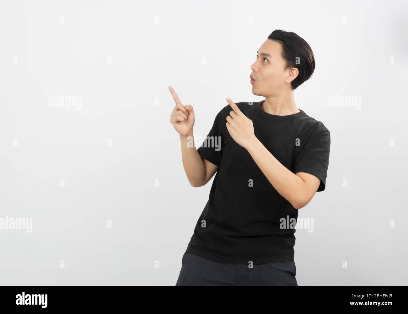 Young asian man with black shirt pointing to the side with a finger to ...