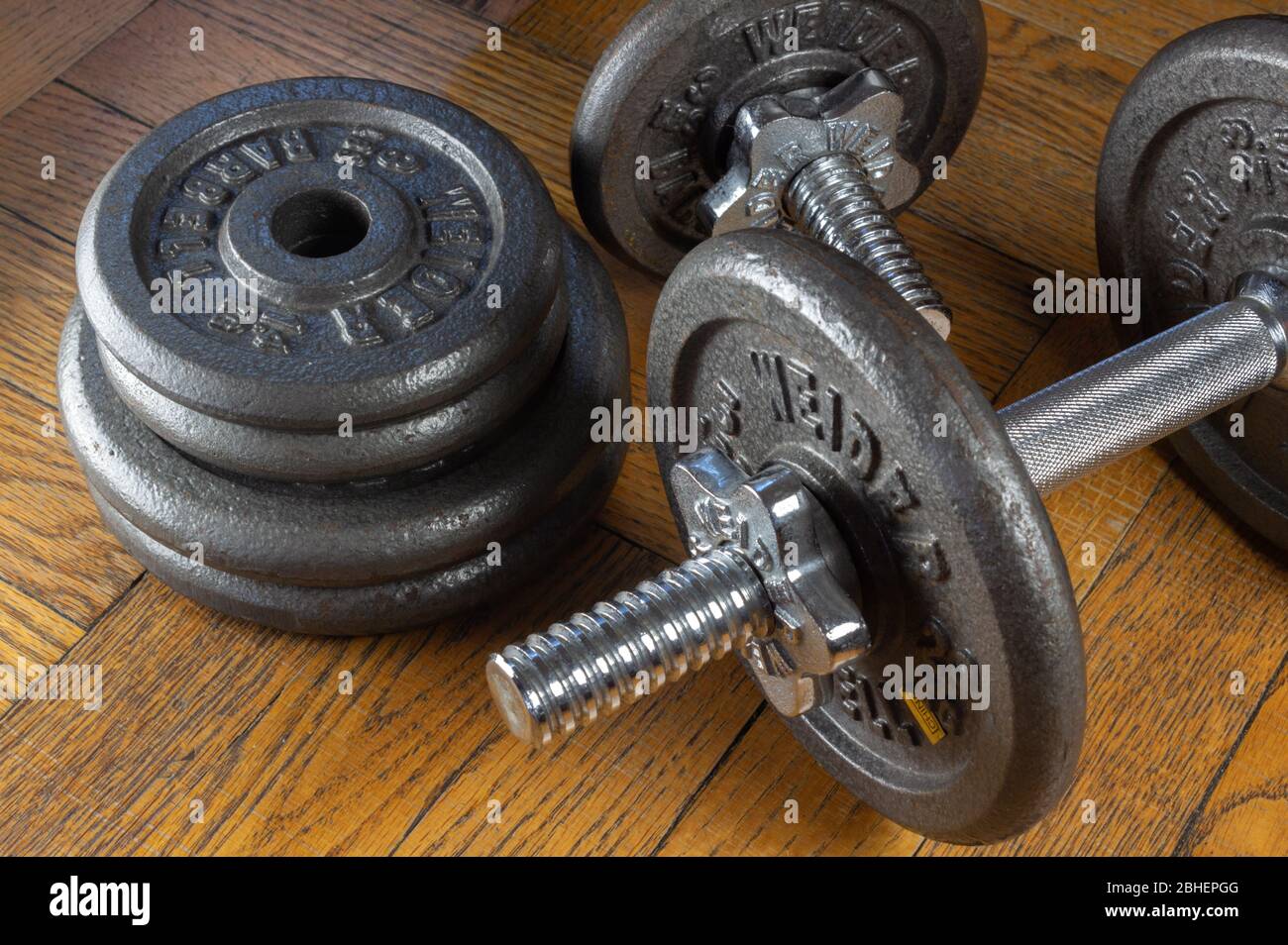 https://c8.alamy.com/comp/2BHEPGG/llustrative-editorial-of-weider-brand-adjustable-dumbbell-free-weights-on-a-wooden-background-2BHEPGG.jpg