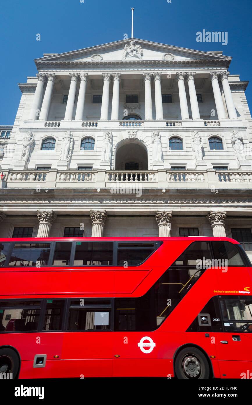 Front facade of the Bank of England building and a modern eco-friendly red London double-decker bus on Threadneedle St, London, EC2R 8AH. The banks controls interest rate levels for the UK Stock Photo