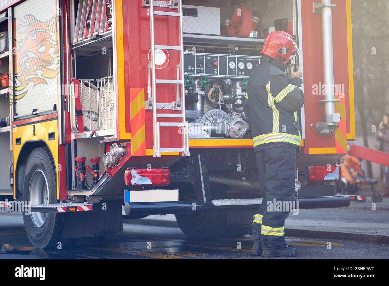 Firefighter in dangerous fire fighting operation. Firefighter in protective clothing, helmets and mask. Stock Photo