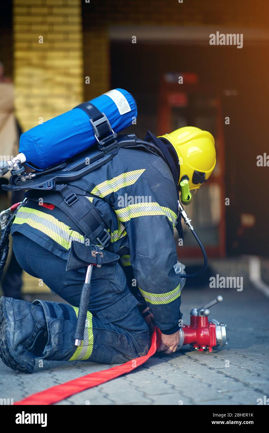 Profesional fireman connection a firehose to a connector device for water for extinguishing fires. Stock Photo
