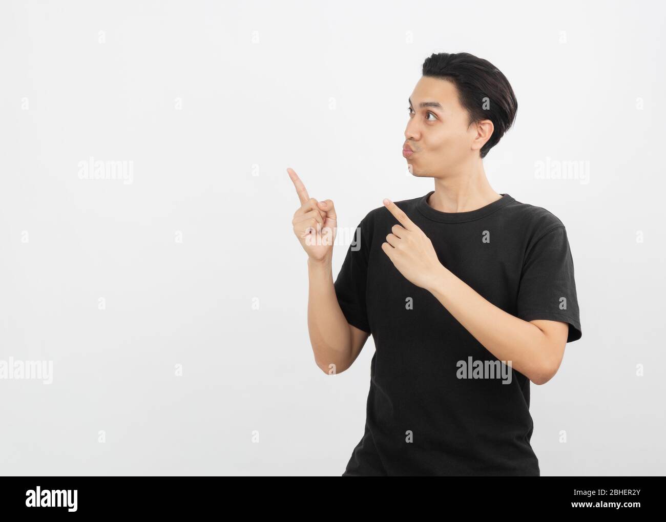 Young asian man with black shirt pointing to the side with a finger to ...