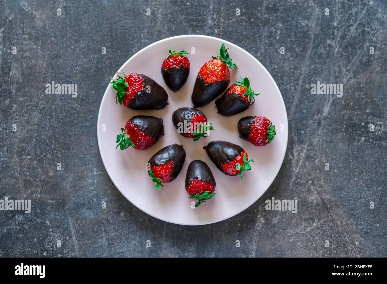 Top view of fresh healthy strawberries dipped in dark chocolate on a plate Stock Photo