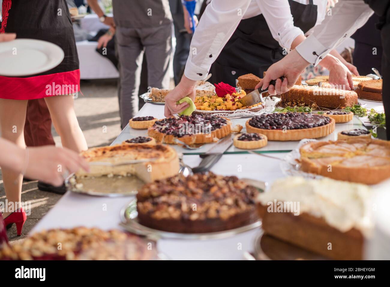 cake buffet with waiters serving and festivepeople taking their parts on the outside Stock Photo