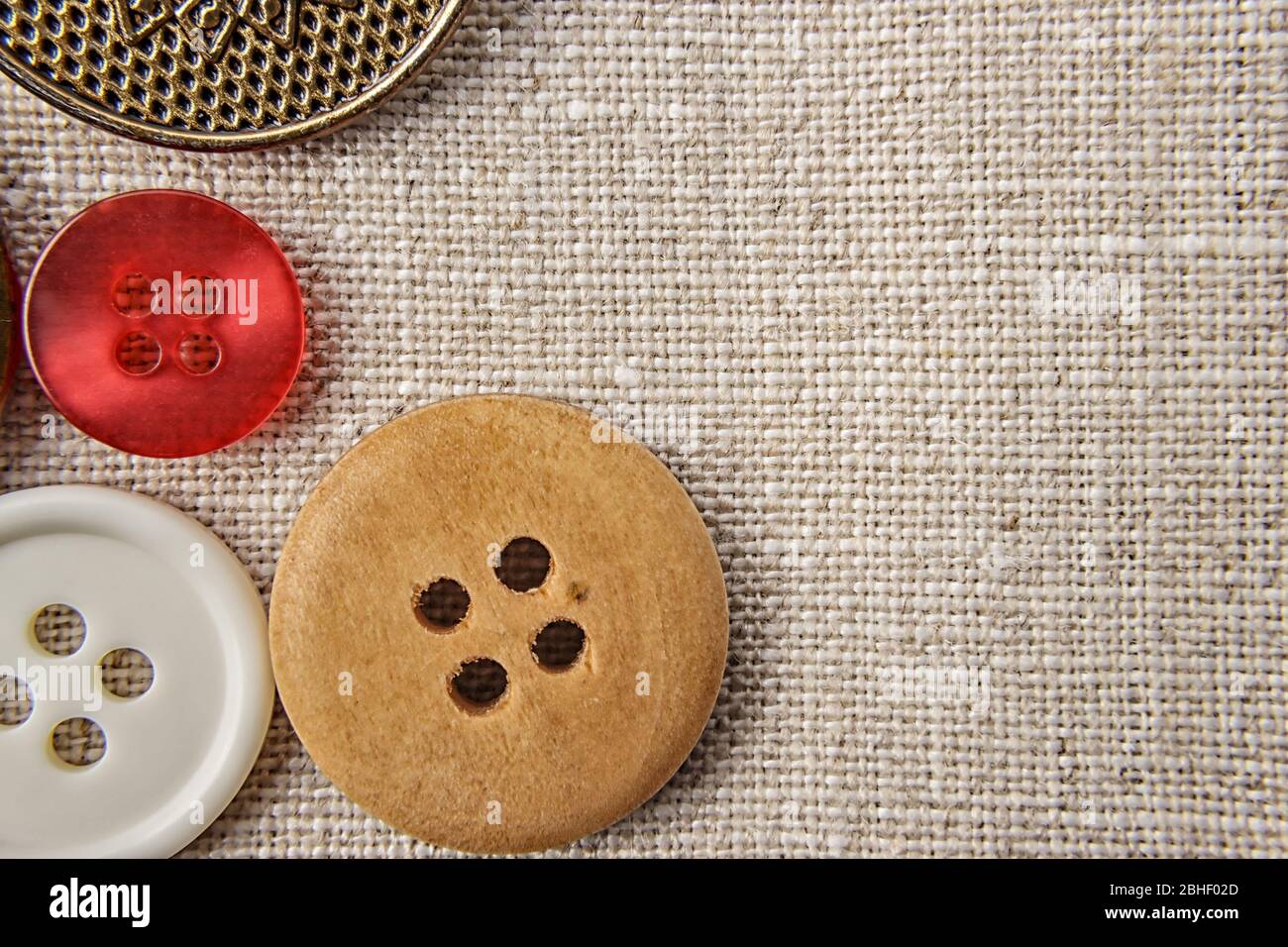 Sewing buttons of various sizes and colors on sackcloth. Stock Photo