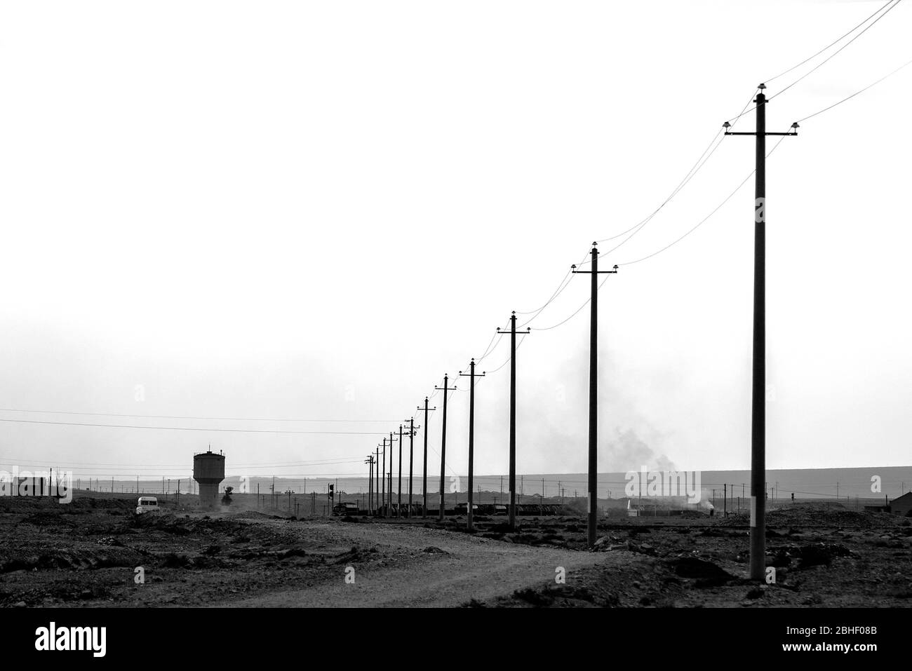 Row of electricity poles and a water tower, on the large and dry landscape near Jiayuguan, not far from the eastern end of The Great Wall, Gansu, Chin Stock Photo