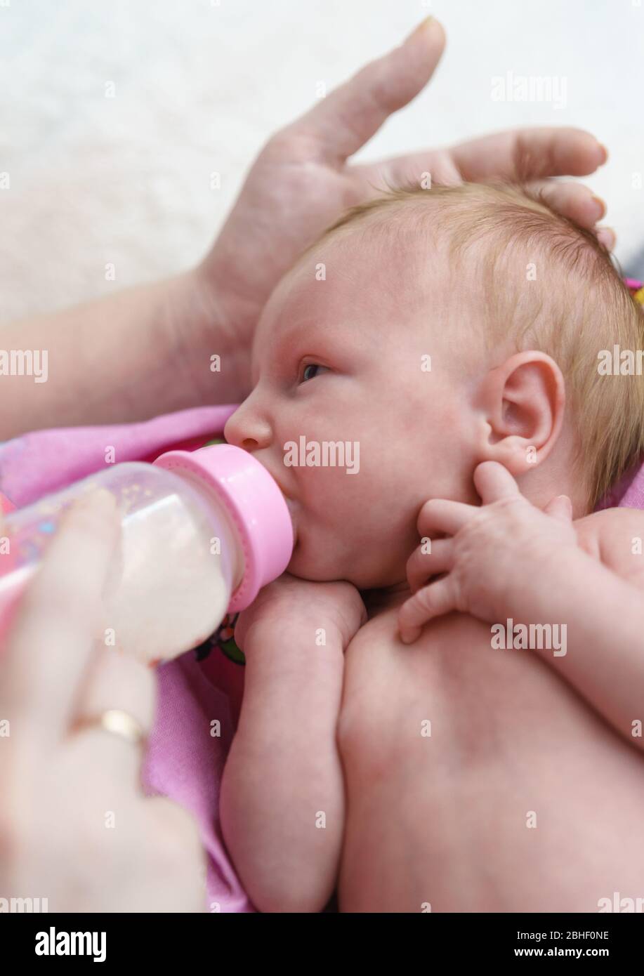 The lure of artificial food. A newborn baby is fed from a bottle. My mothers hand is gently stroking my head Stock Photo