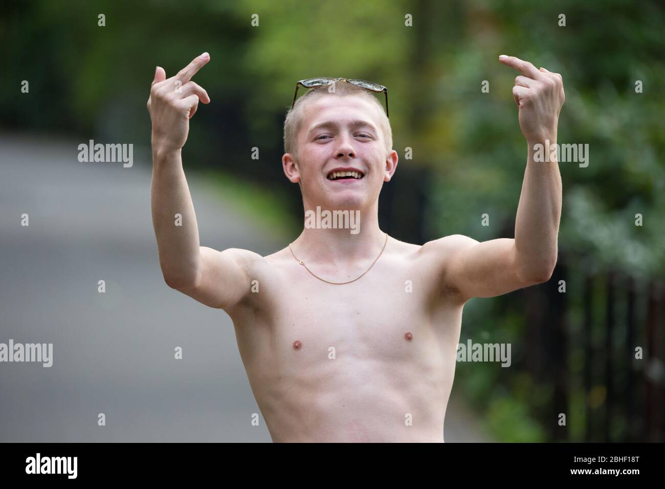 Glasgow, UK. 25th Apr, 2020. Pictured: Keiran Macginley, enjoying the sunshine in the park and giving a friendly gesture to the camera. As the saying goes in Glasgow if the sun is out it's “taps aff” weather. Scenes from the first weekend of the extended lockdown from KelvinGrove Park in Glasgow's West End during a very hot and sunny Saturday. Credit: Colin Fisher/Alamy Live News Stock Photo