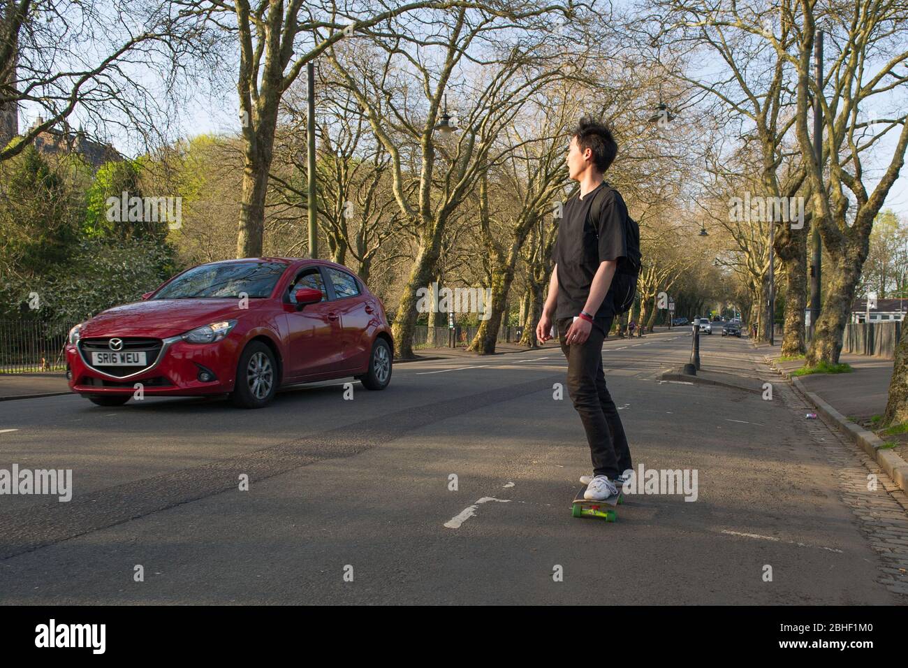 Glasgow, UK. 25th Apr, 2020. Pictured: A skate boarder travels down the road beside the park. Scenes from the first weekend of the extended lockdown from KelvinGrove Park in Glasgow's West End during a very hot and sunny Saturday. Credit: Colin Fisher/Alamy Live News Stock Photo