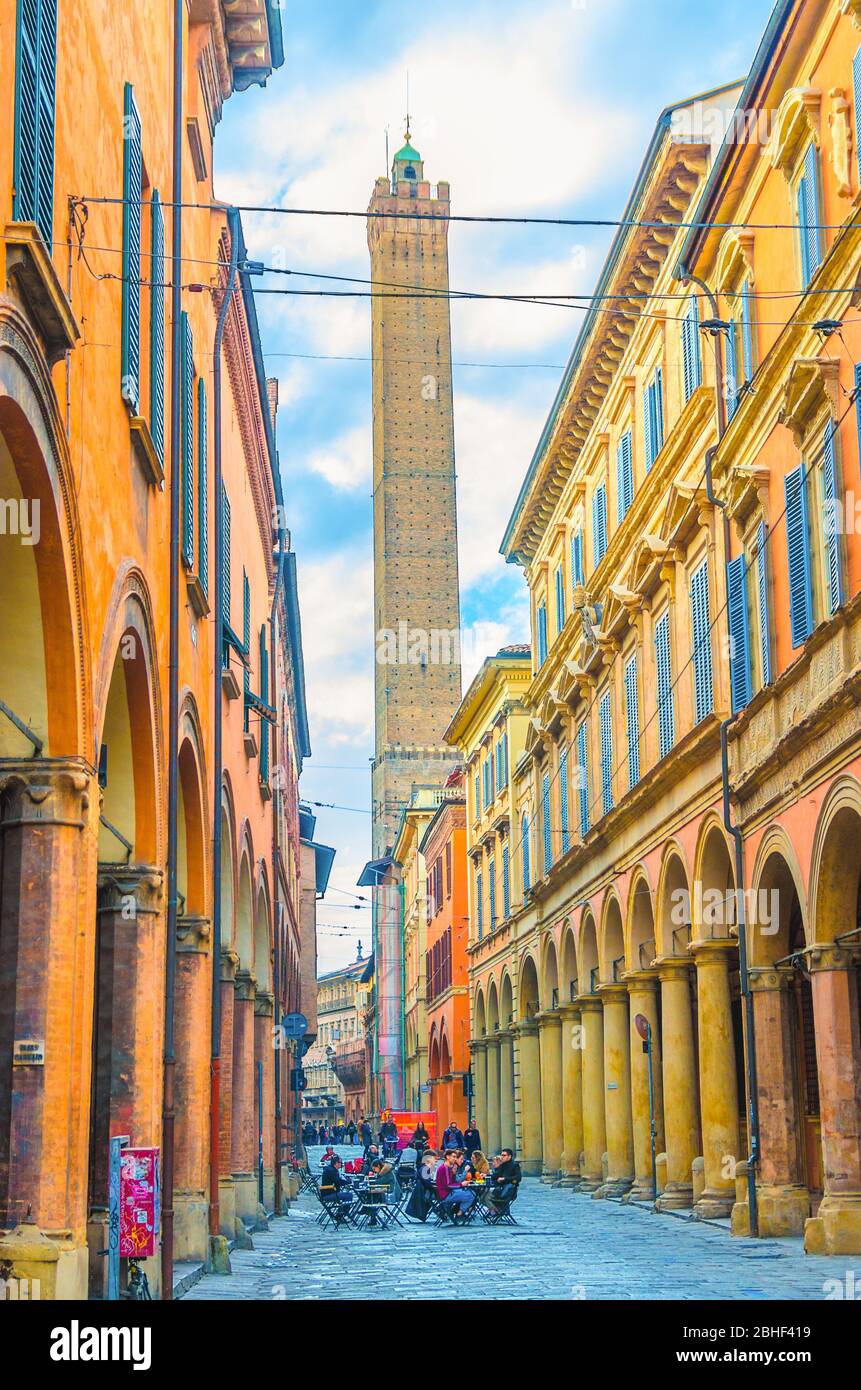 Bologna, Italy, March 17, 2018: typical italian street, buildings with columns and Garisenda medieval tower in old historical city centre, Emilia-Romagna Stock Photo