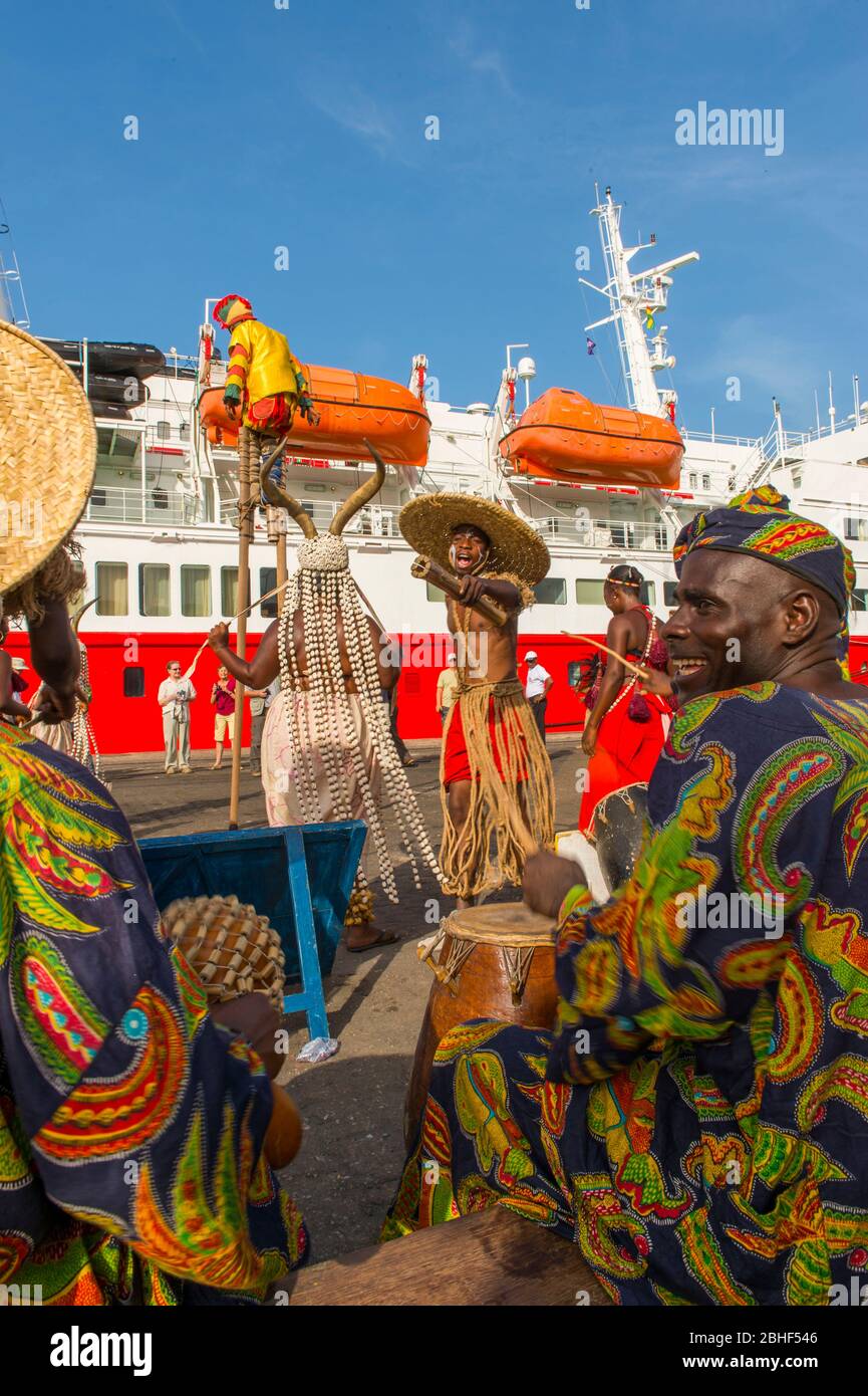 Cultural performance with dancers, a man on stilts and musicians in front of the MS Expedition in the port of Lome, Togo. Stock Photo