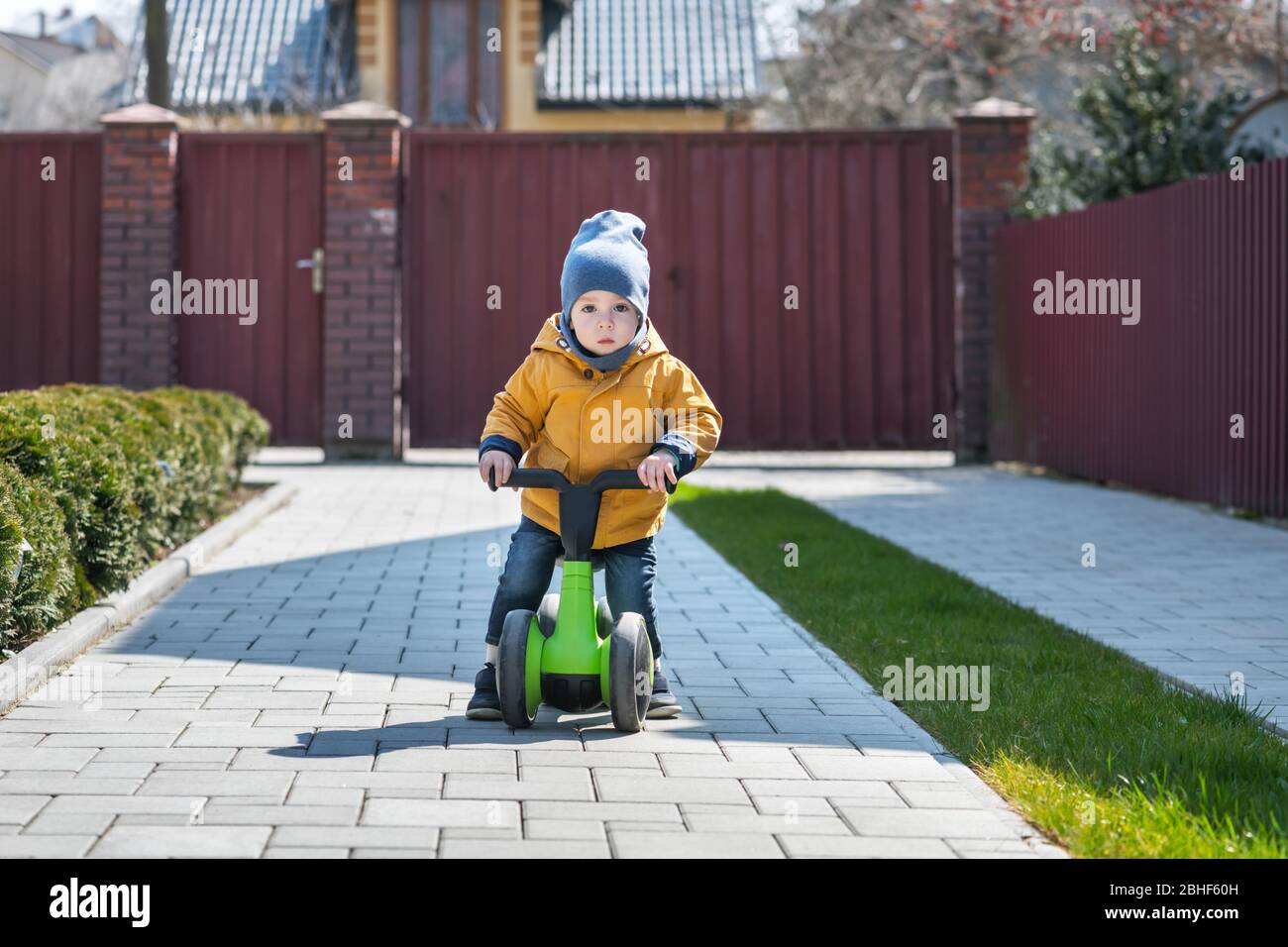 Little boy on his bike on paving path near his house. Happy childhood concept Stock Photo