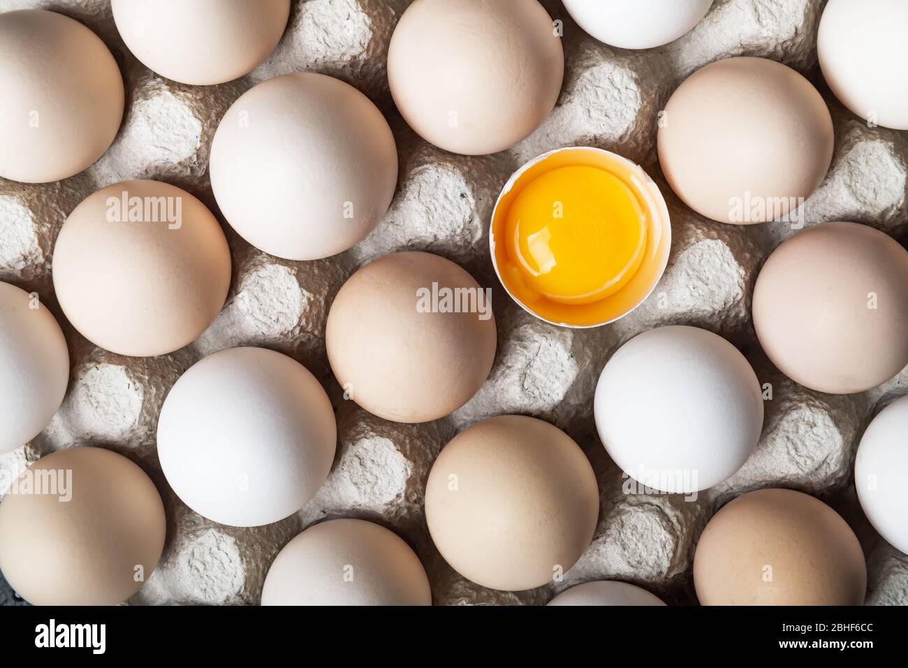 Chicken eggs in organic packaging closeup. Egg half broken among other eggs. Food photography Stock Photo