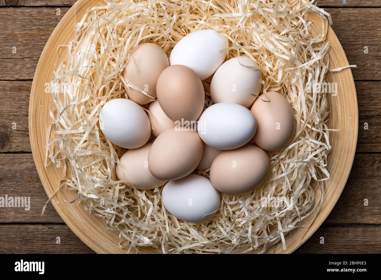 Organic chicken eggs in nest on wooden background. Food photography Stock Photo