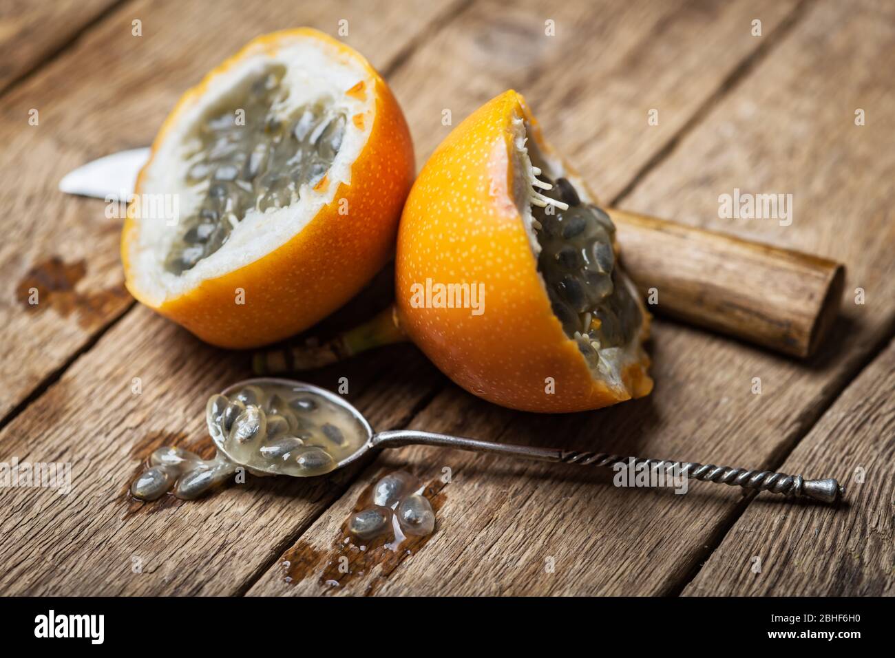 Slised passion fruit with knife and spoon on rusty wooden background. Food photography Stock Photo