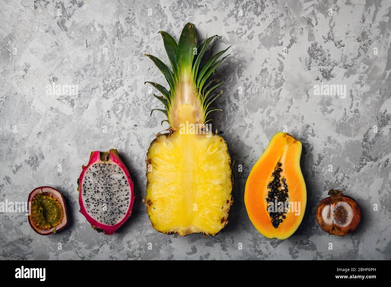Pineapple, Papaya, Passion fruit Maracuya, Dragon fruit Pitaya and Mangosteen on grey concrete background. Exotic tropical fruits concept. Food photography Stock Photo